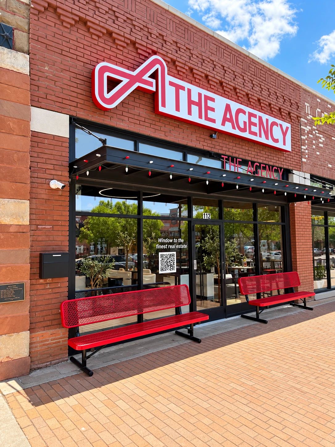 The Agency Oklahoma office storefront on South Broadway in downtown Edmond, with the red The Agency sign and two red benches out front